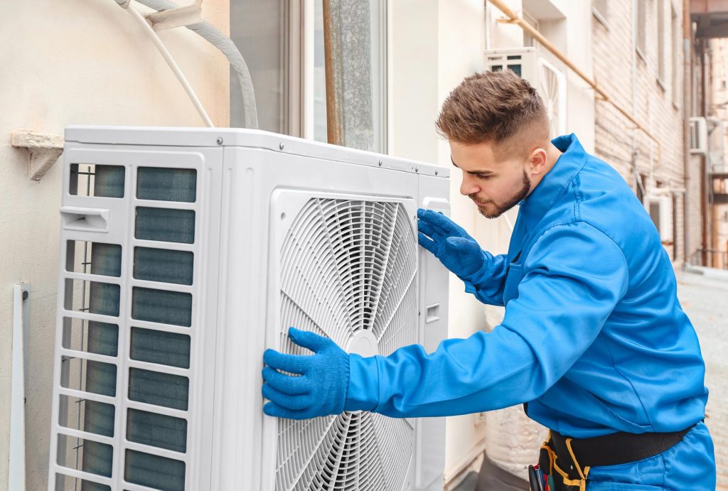 Technician mounting a ductless mini-split indoor unit on an interior wall